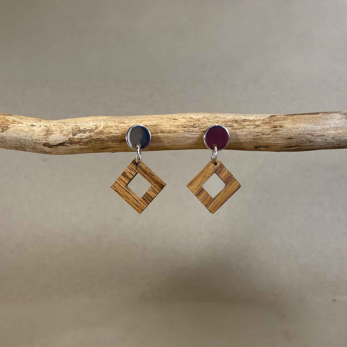 boucles d'oreilles clous carrés femme en bois de noyer et acier argenté, accrochées à une branche, fabrication artisanale française, racines artisanat