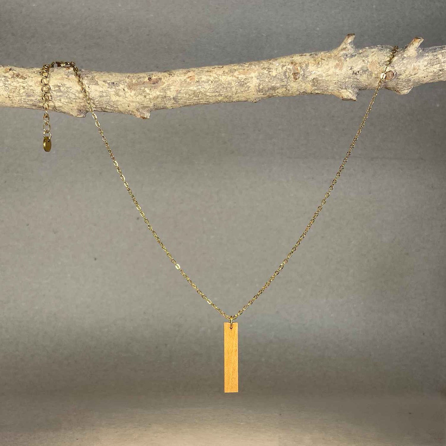 collier pendentif barre femme en bois de merisier et acier doré, suspendu à une branche, fabrication artisanale française, racines artisanat