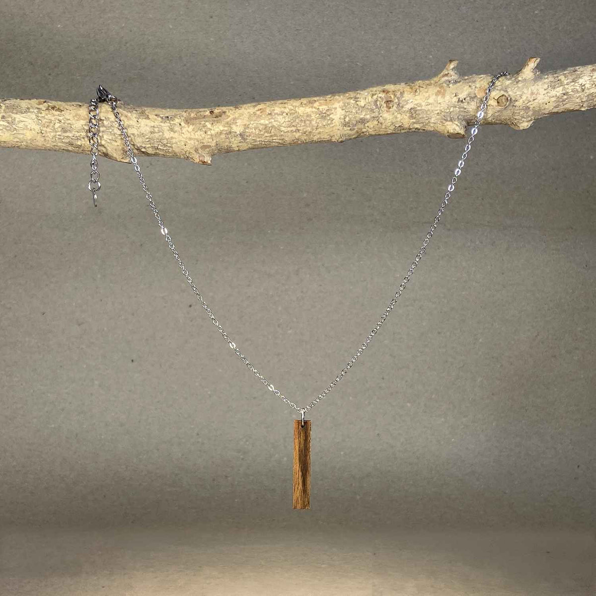 collier barre femme en bois de noyer et acier argenté, suspendu à une branche, fabrication artisanale française, racines artisanat