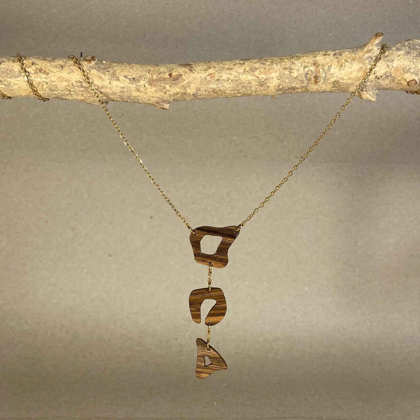 collier léopard femme en bois de noyer et acier doré, suspendu à une branche, fabrication artisanale française, racines artisanat