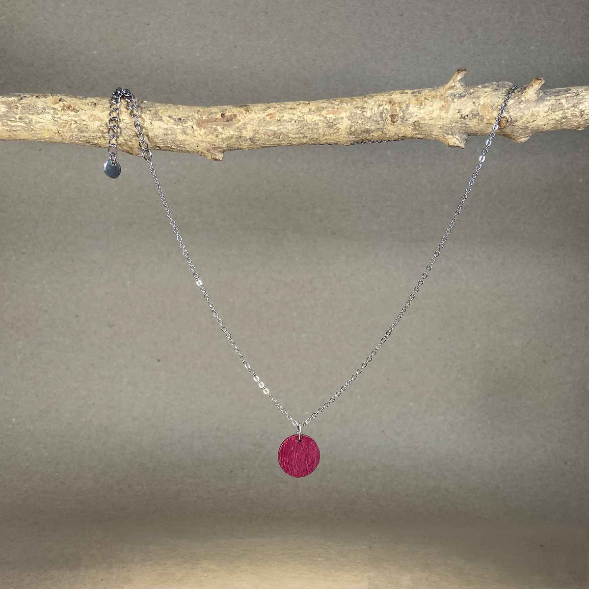 collier pendentif rond femme en bois d'amarante et acier argenté, suspendu à une branche, fabrication artisanale française, racines artisanat