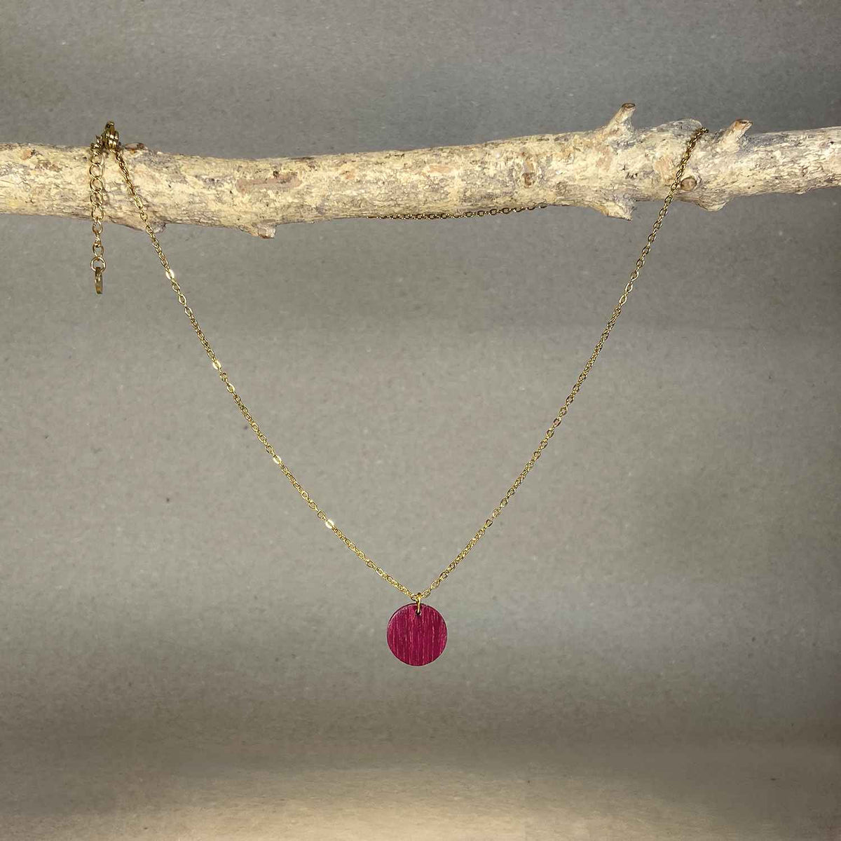 collier pendentif rond femme en bois d'amarante et acier doré, suspendu à une branche, fabrication artisanale française, racines artisanat
