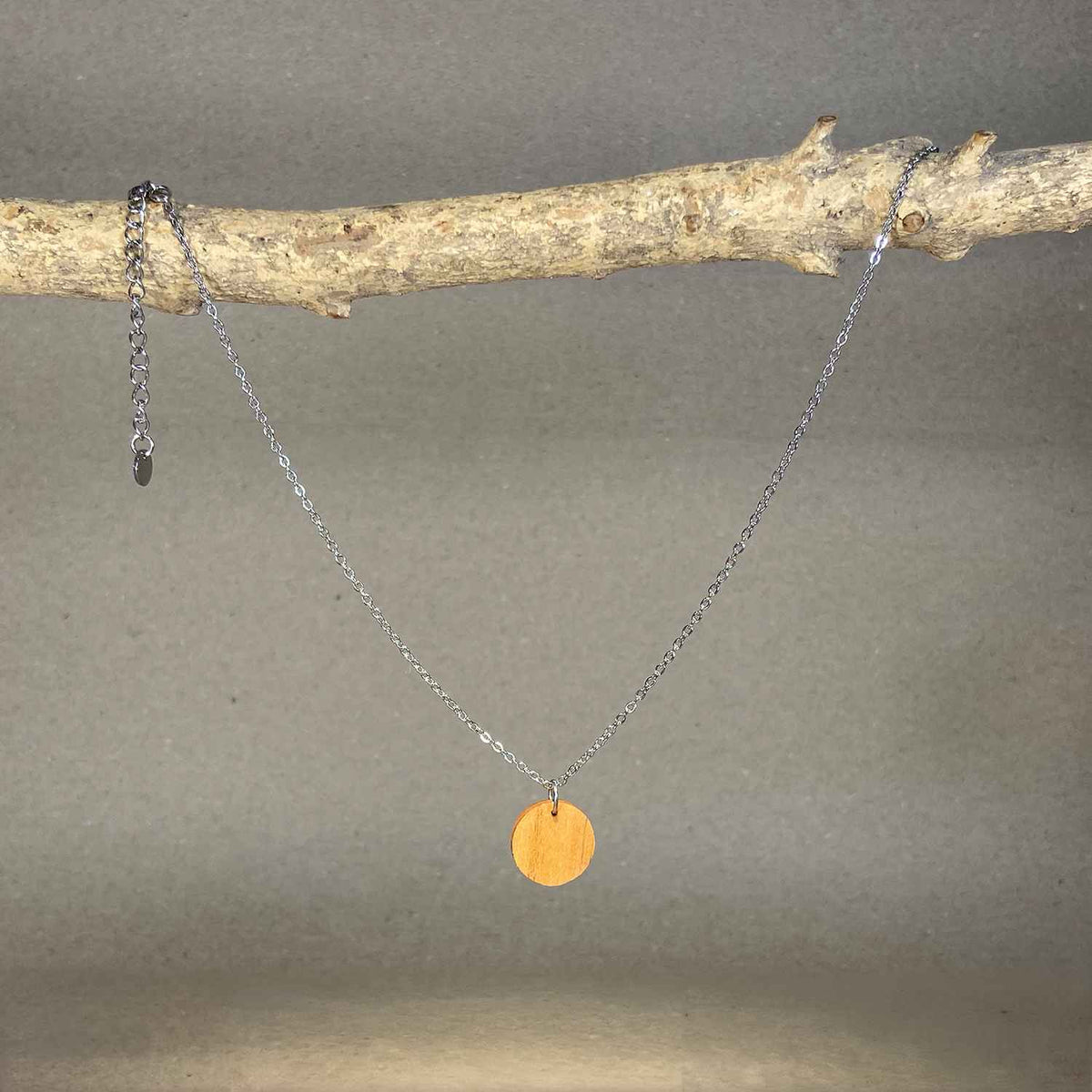 collier pendentif rond femme en bois de merisier et acier argenté, suspendu à une branche, fabrication artisanale française, racines artisanat