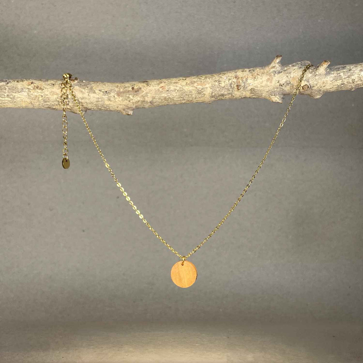 collier pendentif rond femme en bois de merisier et acier doré, suspendu à une branche, fabrication artisanale française, racines artisanat