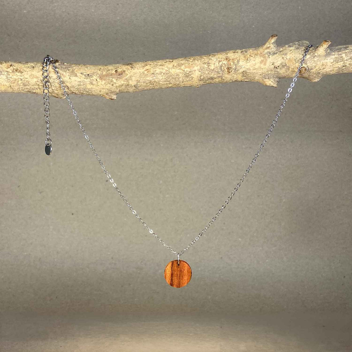 collier pendentif rond femme en bois de rose et acier argenté, suspendu à une branche, fabrication artisanale française, racines artisanat