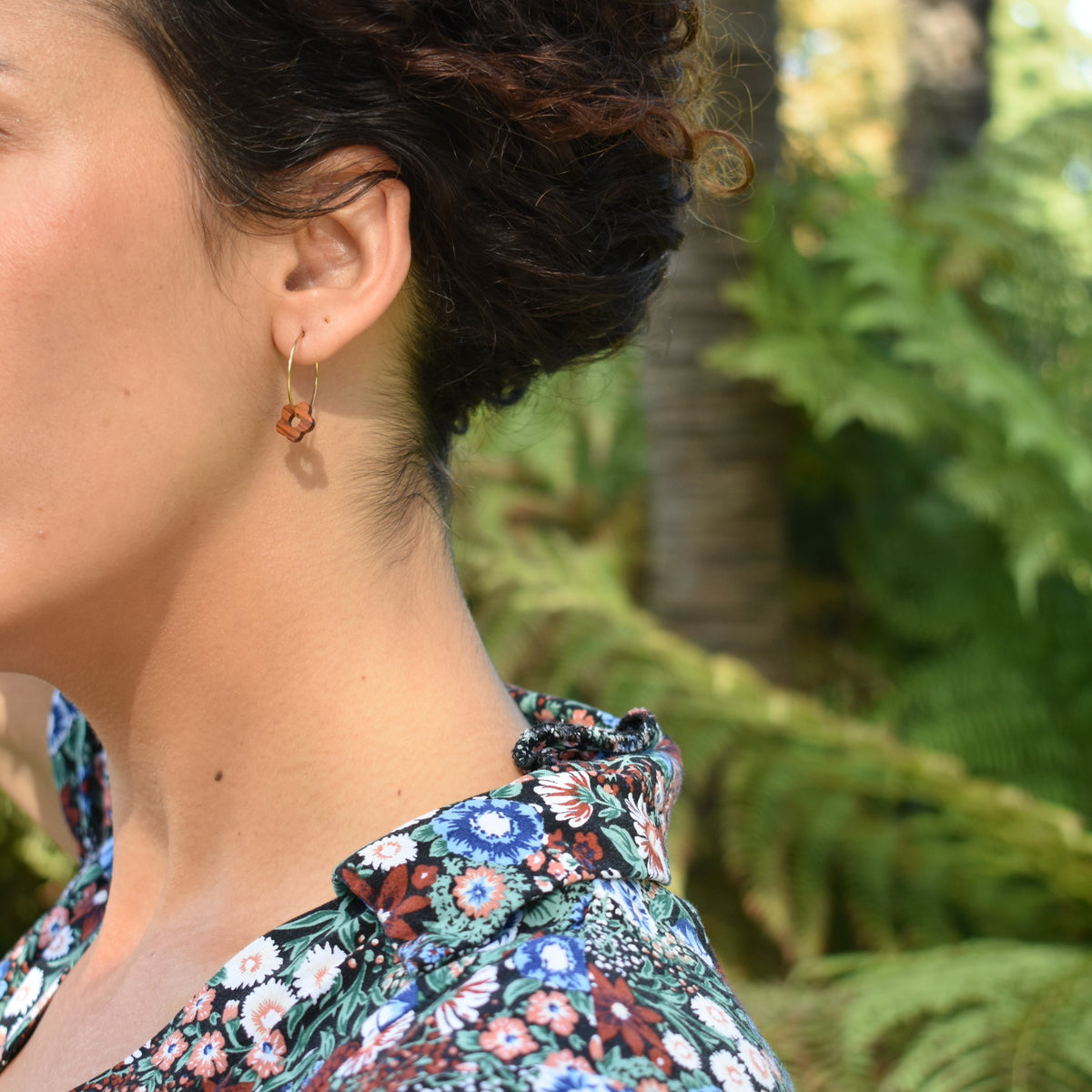 boucles d'oreilles créoles marguerite femme en bois de merisier et acier argenté, portées à une oreille, fabrication artisanale française, racines artisanat