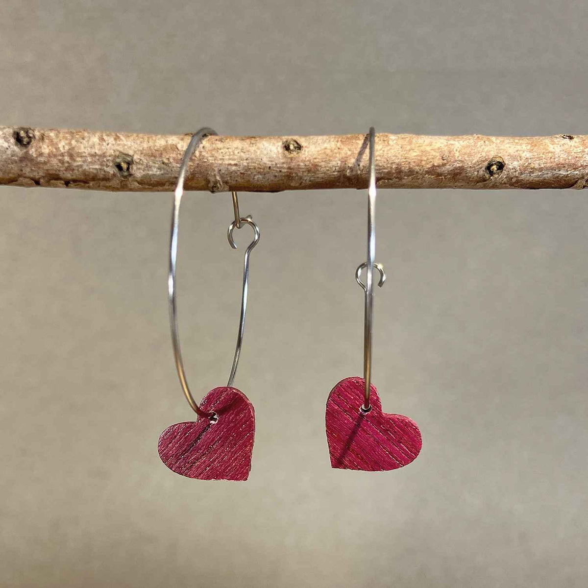 boucles d'oreilles créoles coeur femme en bois d'amarante et acier argenté, suspendues à une branche, fabrication artisanale française, racines artisanat