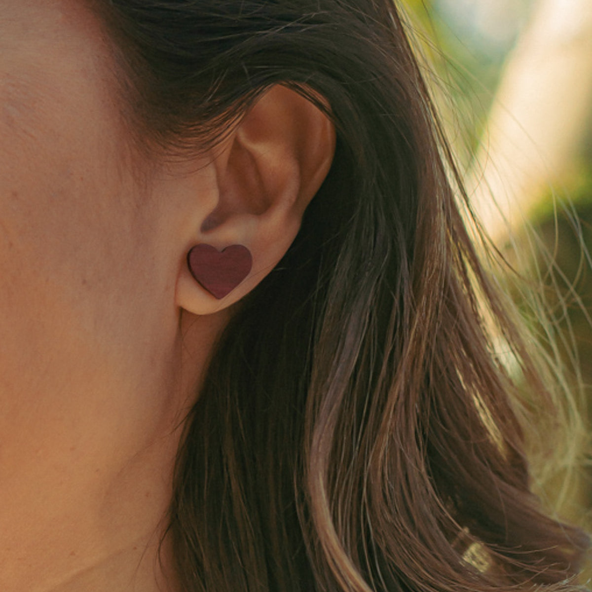 puces d'oreilles coeur femme en bois d'amarante, portées à une oreille, fabrication artisanale française, racines artisanat