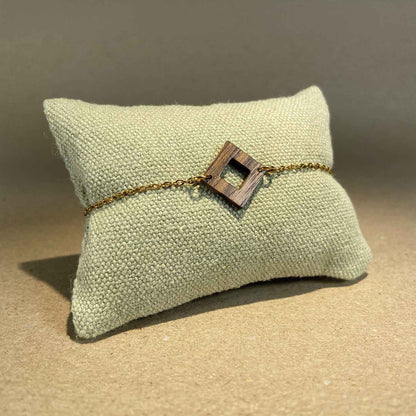 bracelet carré femme en bois de noyer et acier doré, accroché à un coussin, fabrication artisanale française, racines artisanat