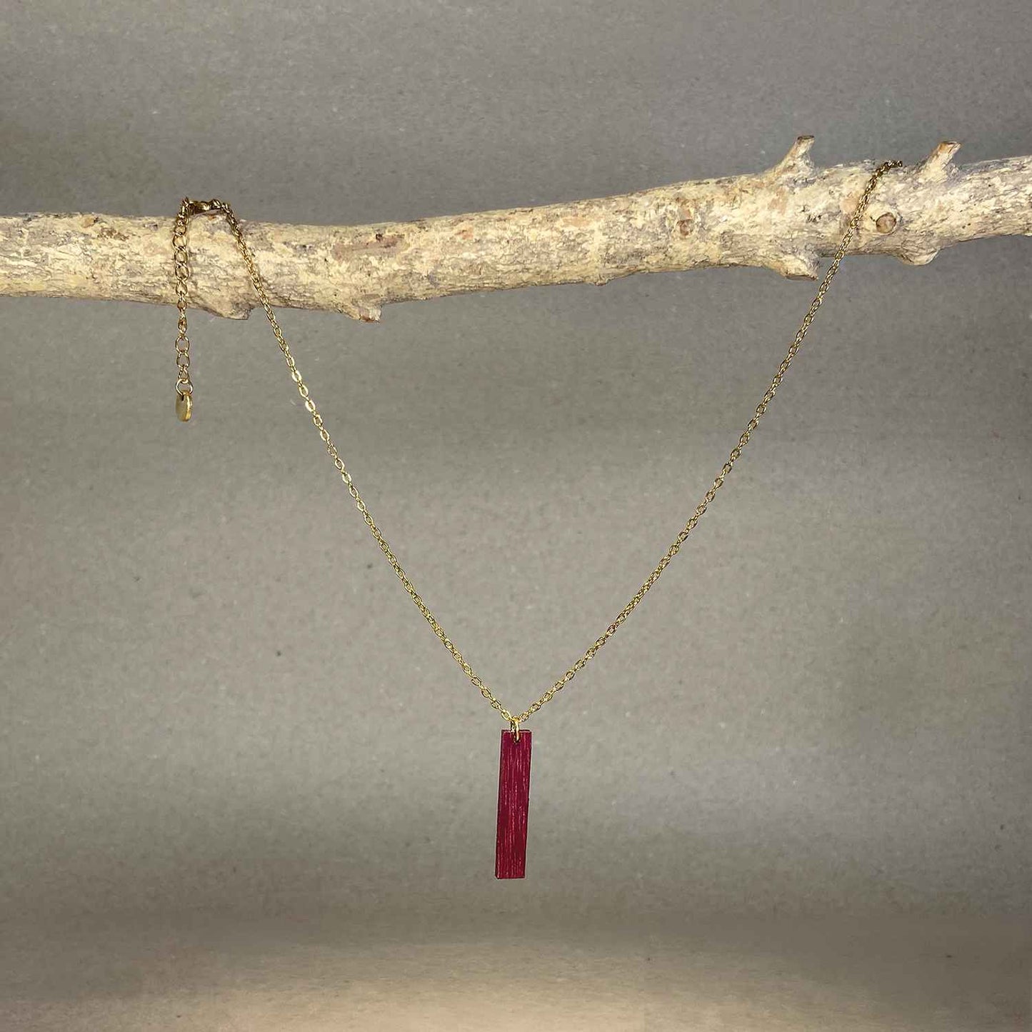 collier pendentif barre femme en bois d'amarante et acier doré, suspendu à une branche, fabrication artisanale française, racines artisanat