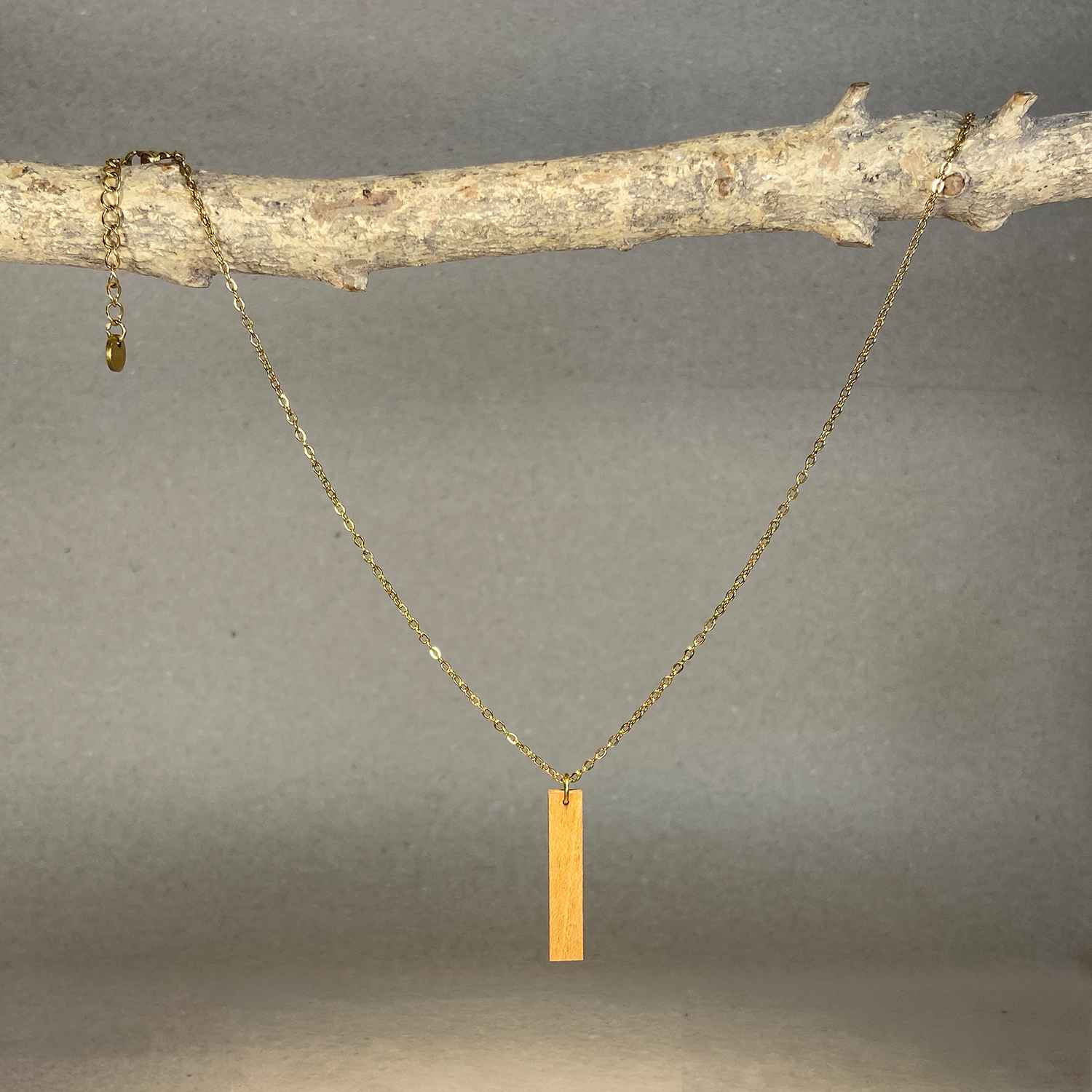 collier pendentif barre femme en bois de merisier et acier doré, suspendu à une branche, fabrication artisanale française, racines artisanat