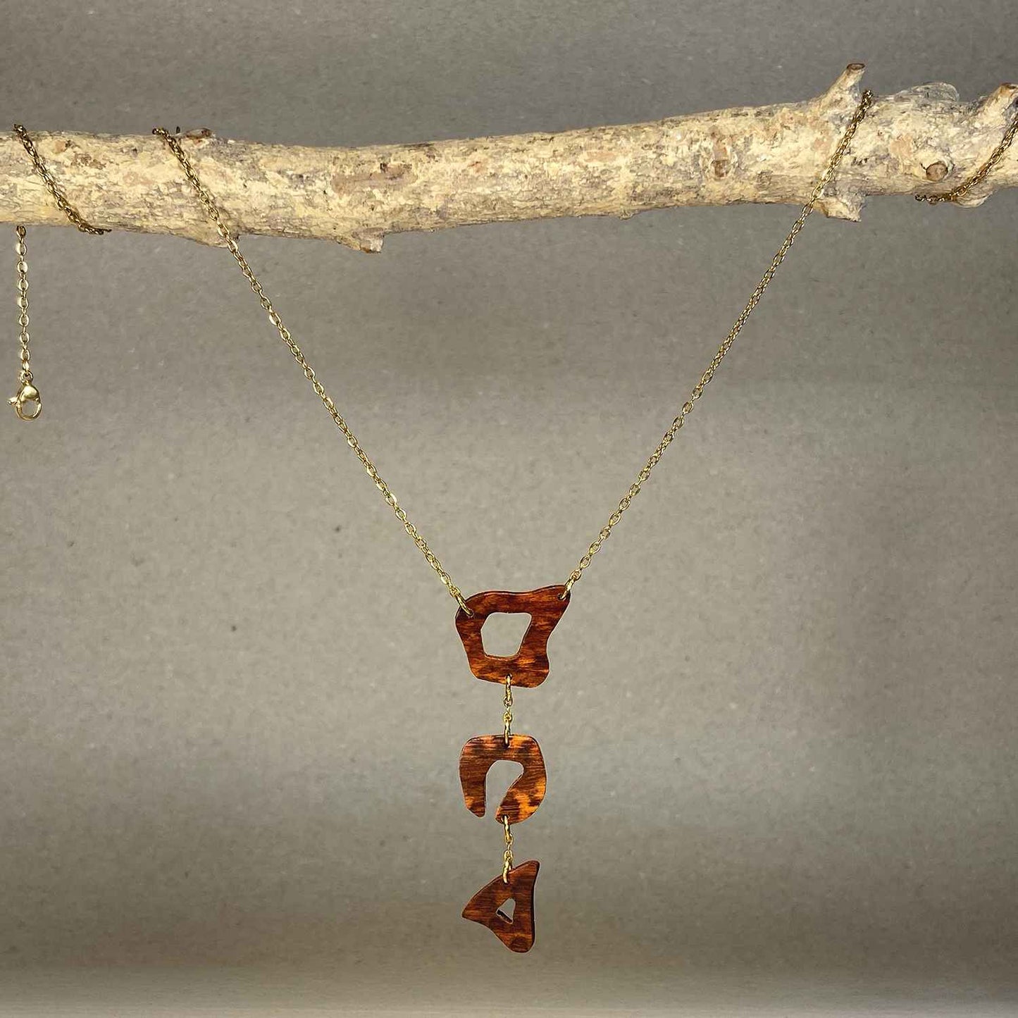 collier léopard femme en bois d'amourette et acier doré, suspendu à une branche, fabrication artisanale française, racines artisanat