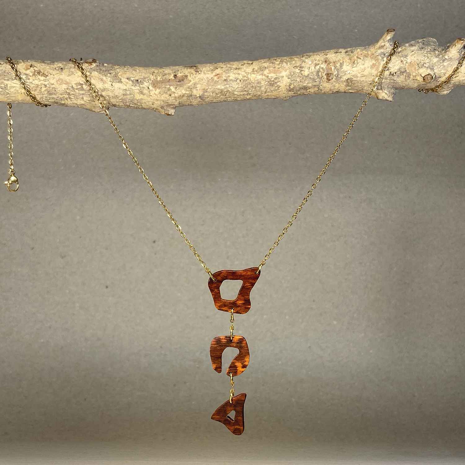 collier léopard femme en bois d'amourette et acier doré, suspendu à une branche, fabrication artisanale française, racines artisanat