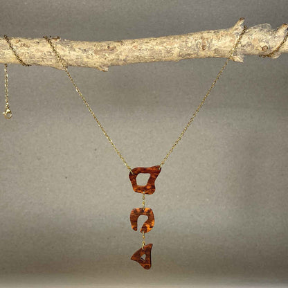 collier léopard femme en bois d'amourette et acier doré, suspendu à une branche, fabrication artisanale française, racines artisanat
