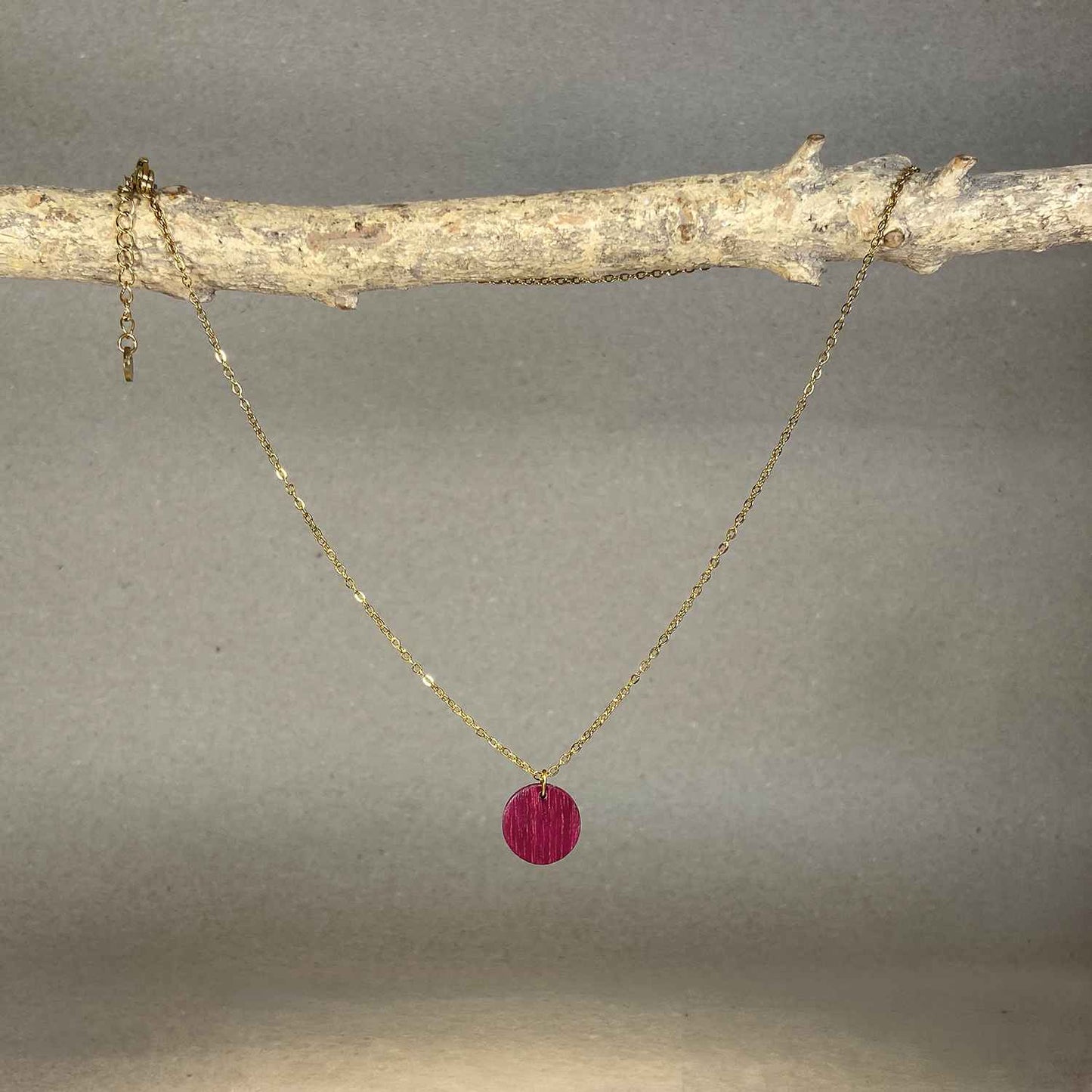 collier pendentif rond femme en bois d'amarante et acier doré, suspendu à une branche, fabrication artisanale française, racines artisanat
