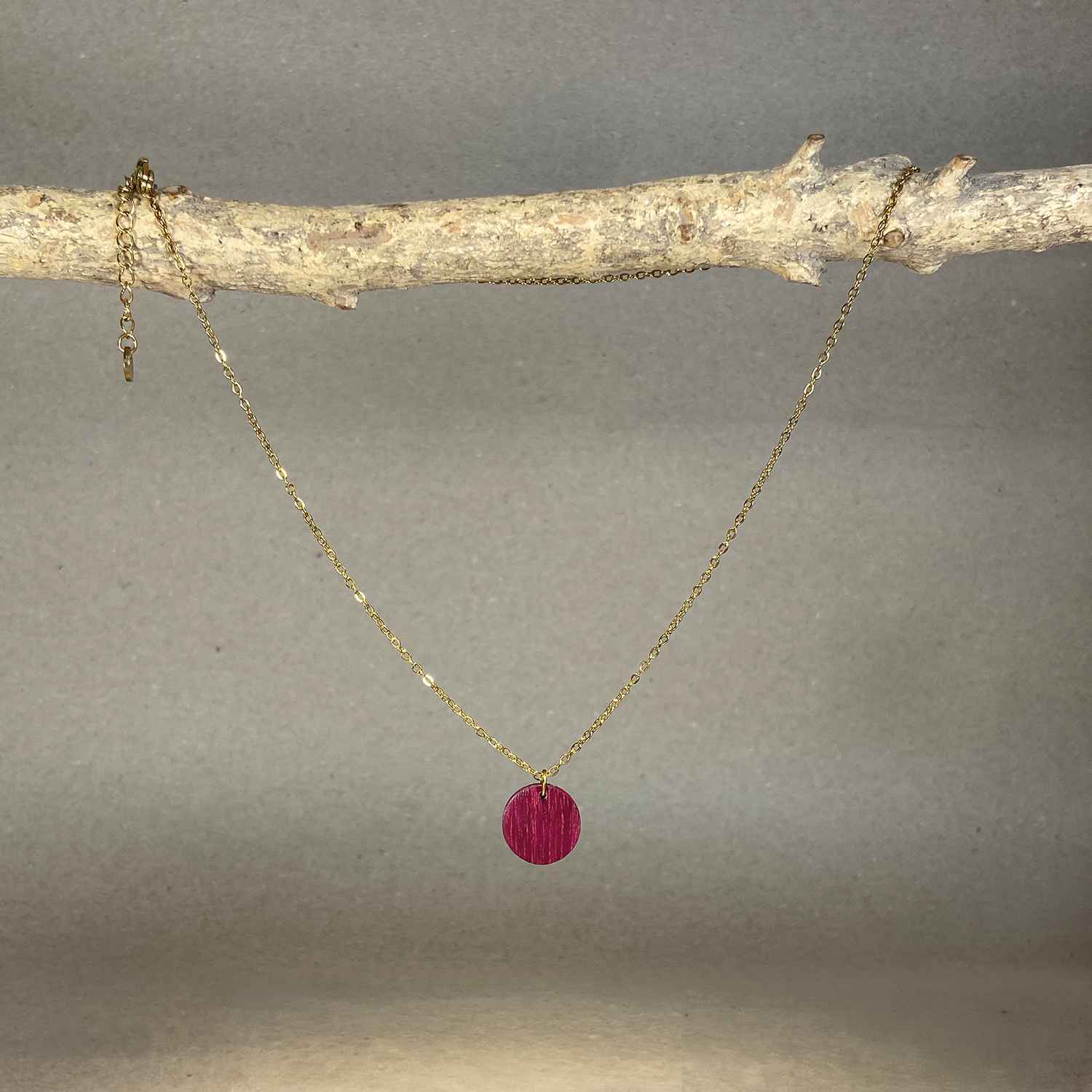 collier pendentif rond femme en bois d'amarante et acier doré, suspendu à une branche, fabrication artisanale française, racines artisanat