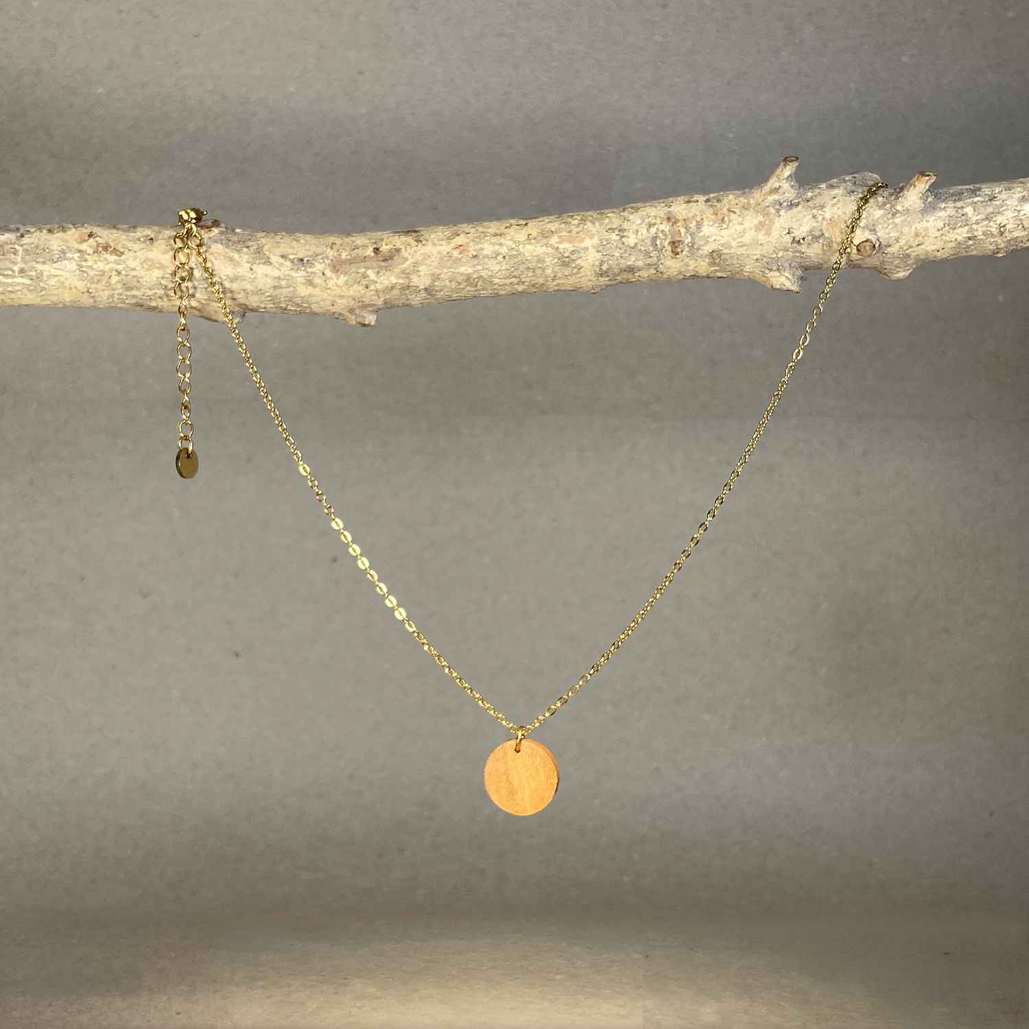 collier pendentif rond femme en bois de merisier et acier doré, suspendu à une branche, fabrication artisanale française, racines artisanat