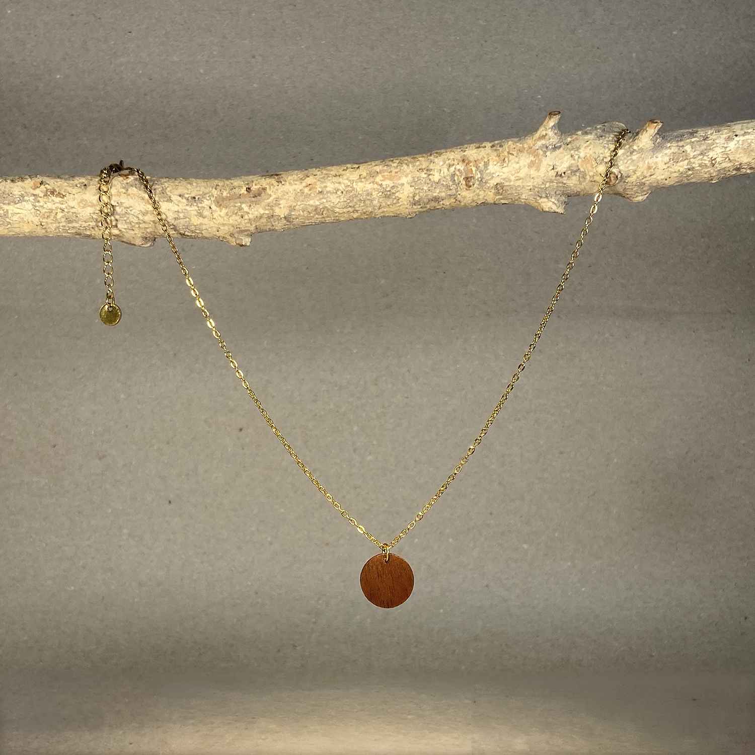 collier pendentif rond femme en bois de noyer et acier doré, suspendu à une branche, fabrication artisanale française, racines artisanat
