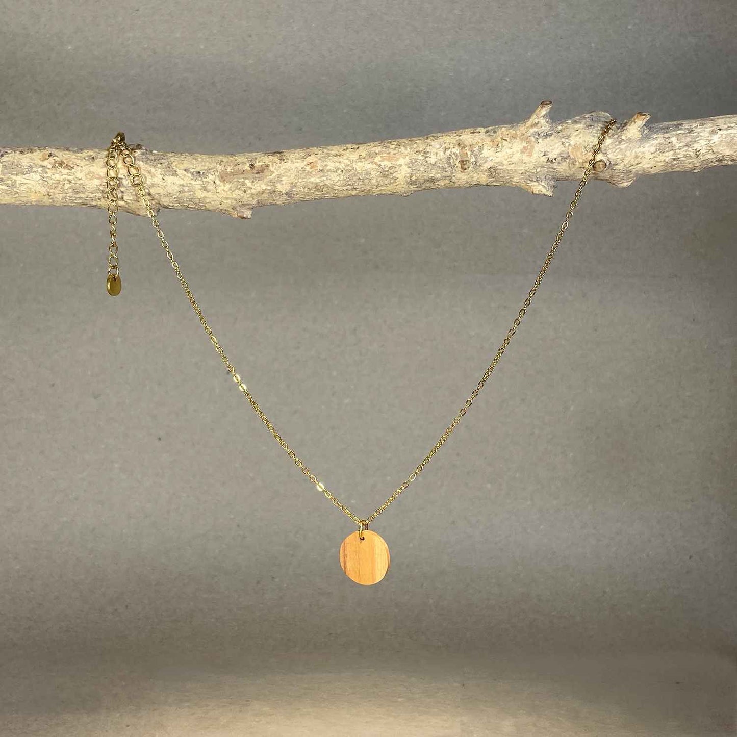 collier pendentif rond femme en bois d'olivier et acier doré, suspendu à une branche, fabrication artisanale française, racines artisanat