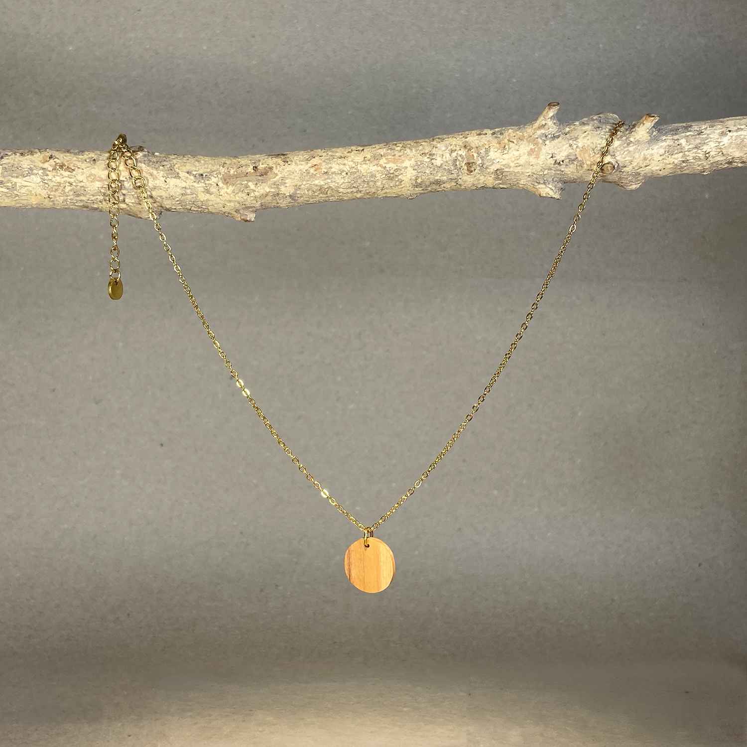 collier pendentif rond femme en bois d'olivier et acier doré, suspendu à une branche, fabrication artisanale française, racines artisanat