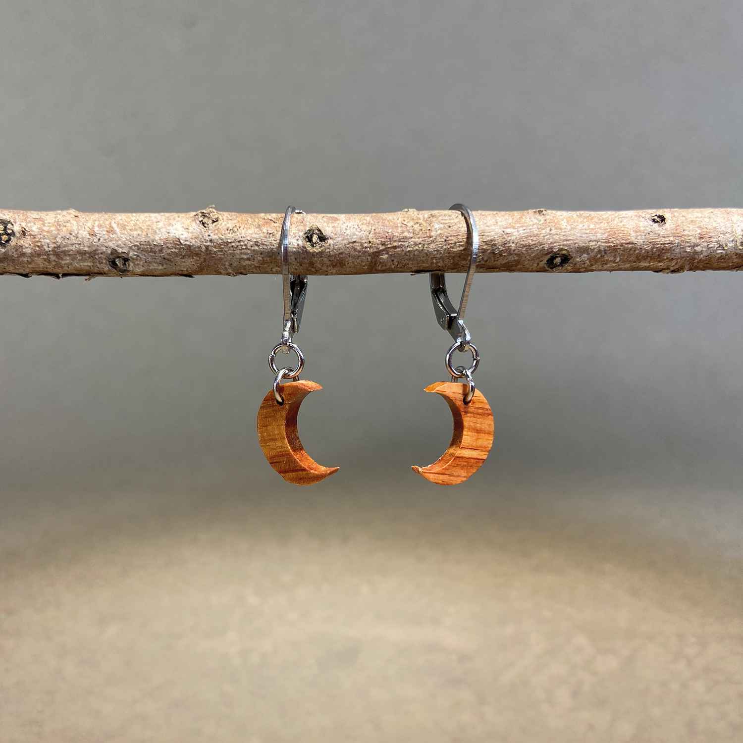 boucles d'oreilles demi-lune femme en bois de rose et acier argenté, suspendues à une branche, fabrication artisanale française, racines artisanat
