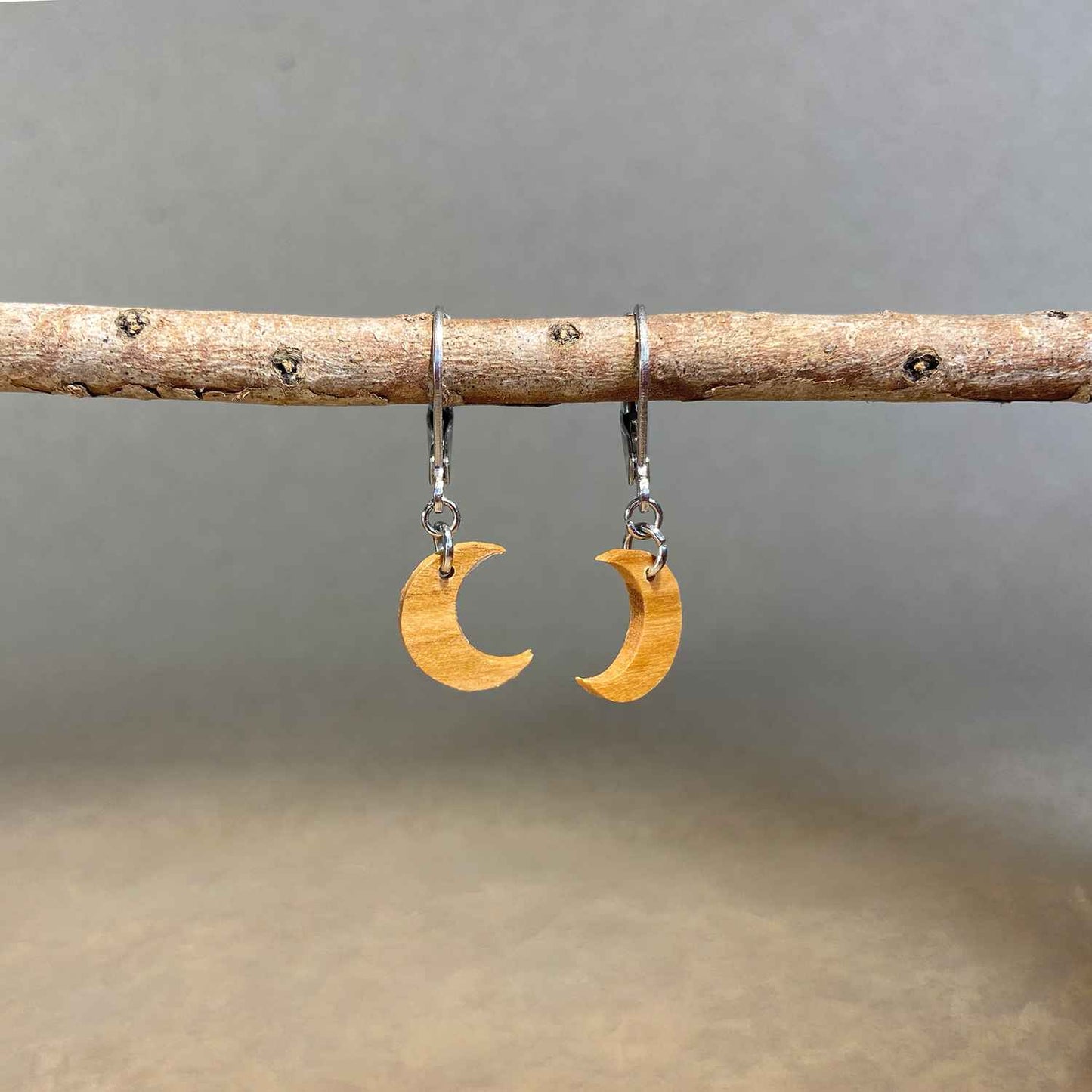 boucles d'oreilles demi-lune femme en bois d'olivier et acier argenté, suspendues à une branche, fabrication artisanale française, racines artisanat