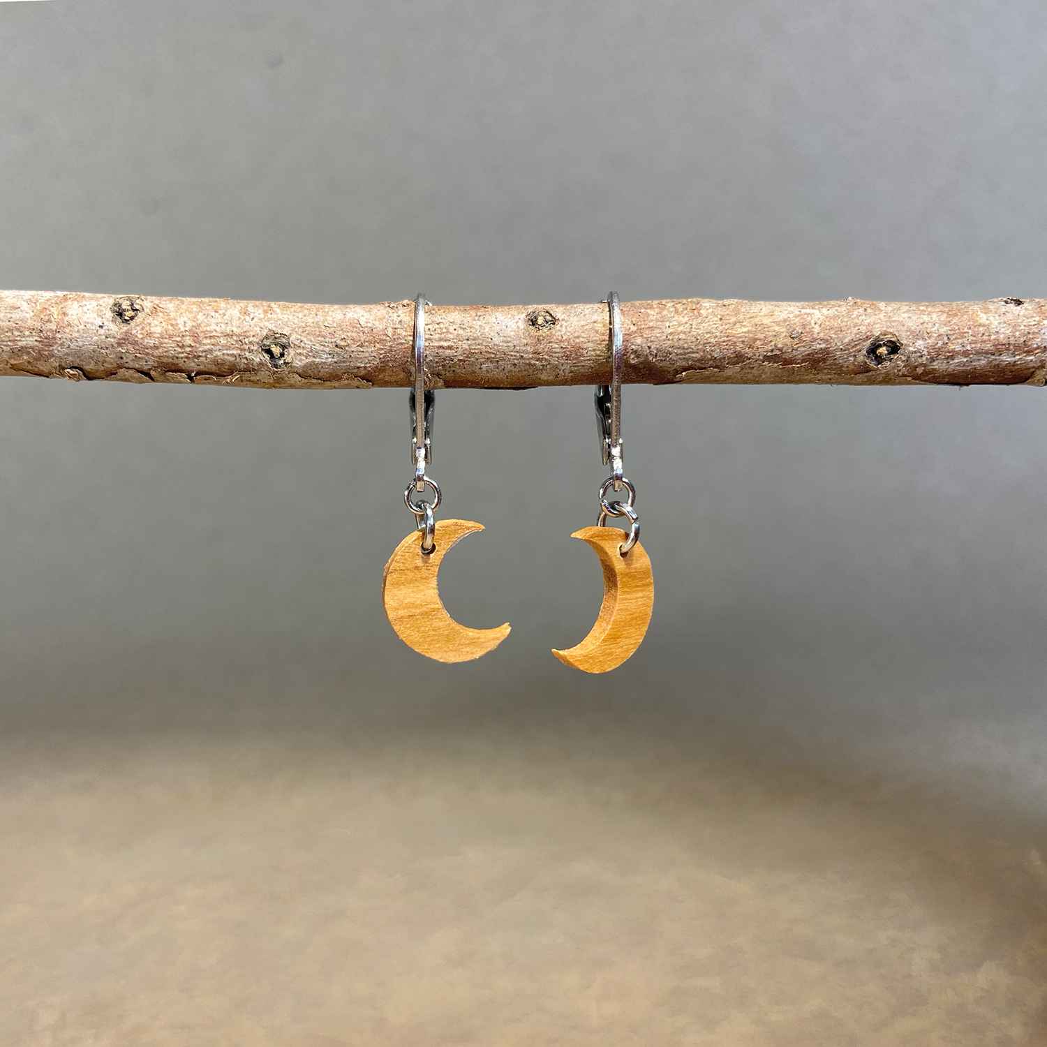 boucles d'oreilles demi-lune femme en bois d'olivier et acier argenté, suspendues à une branche, fabrication artisanale française, racines artisanat