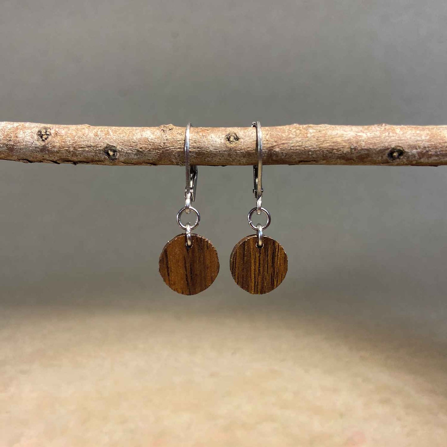boucles d'oreilles rondes femme en bois de noyer et acier argenté, suspendues à une branche, fabrication artisanale française, racines artisanat