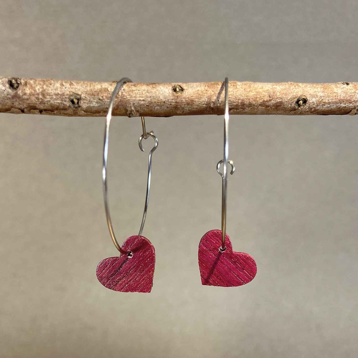 boucles d'oreilles créoles coeur femme en bois d'amarante et acier argenté, suspendues à une branche, fabrication artisanale française, racines artisanat