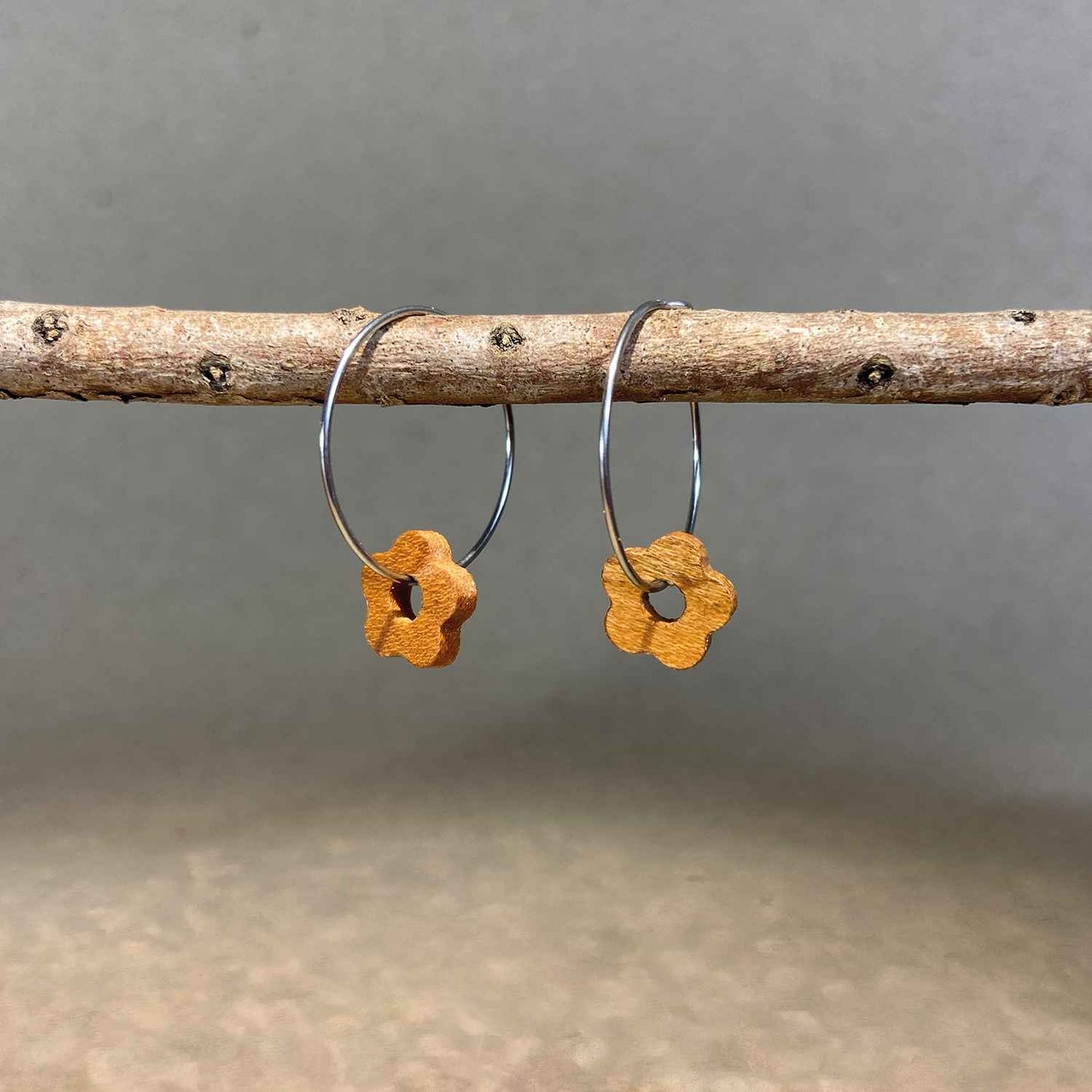 boucles d'oreilles créoles marguerite femme en bois de merisier et acier argenté, suspendues à une branche, fabrication artisanale française, racines artisanat
