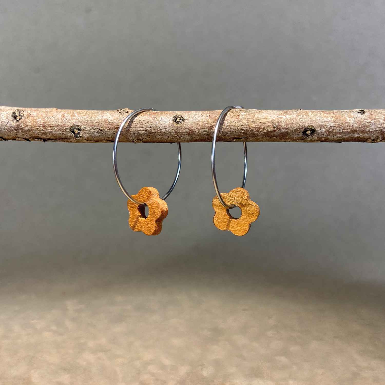 boucles d'oreilles créoles marguerite femme en bois de merisier et acier argenté, suspendues à une branche, fabrication artisanale française, racines artisanat