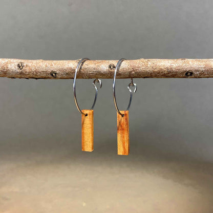 boucles d'oreilles créoles petite barre femme en bois de rose et acier argenté, suspendues à une branche, fabrication artisanale française, racines artisanat