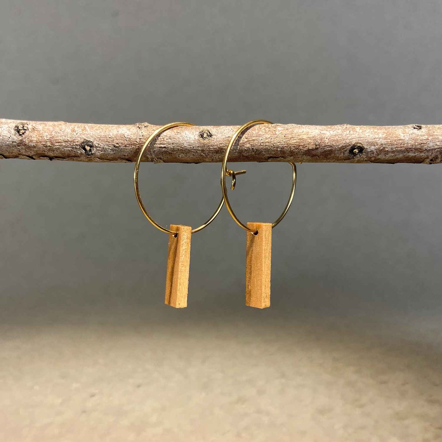 boucles d'oreilles créoles petite barre femme en bois d'olivier et acier doré, suspendues à une branche, fabrication artisanale française, racines artisanat